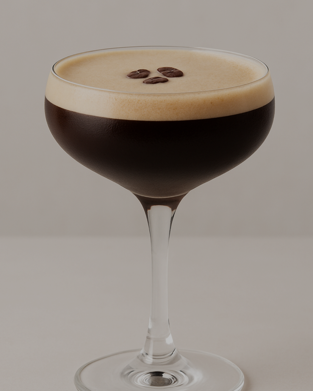 Espresso martini in a coupe glass with a creamy foam top and three coffee beans