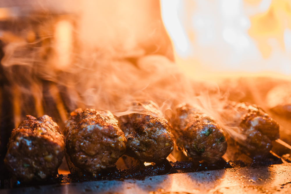 lamb kofta sharing plates with fire cooking on a grill