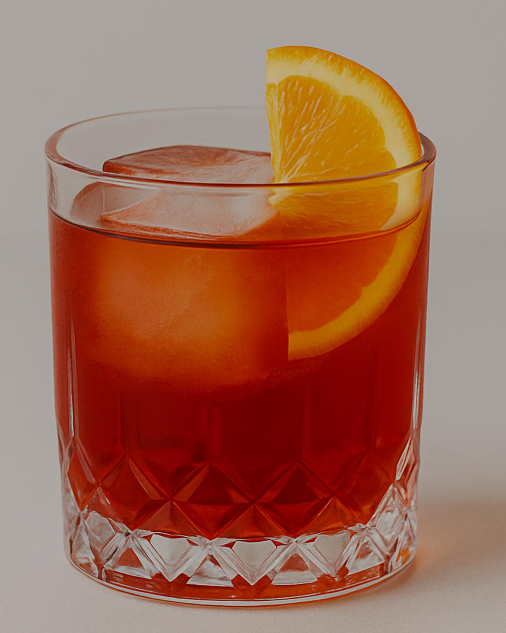 Negroni over a large ice cube in a cut-glass tumbler with an orange wedge