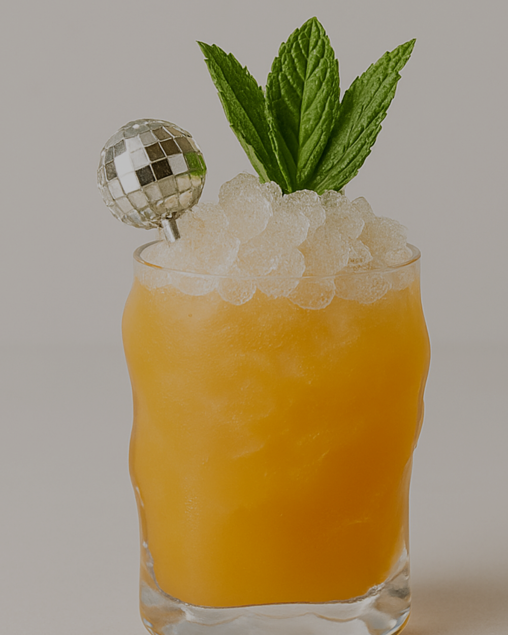 The Socialite, an orange cocktail with crushed ice, mint and a miniature disco ball.