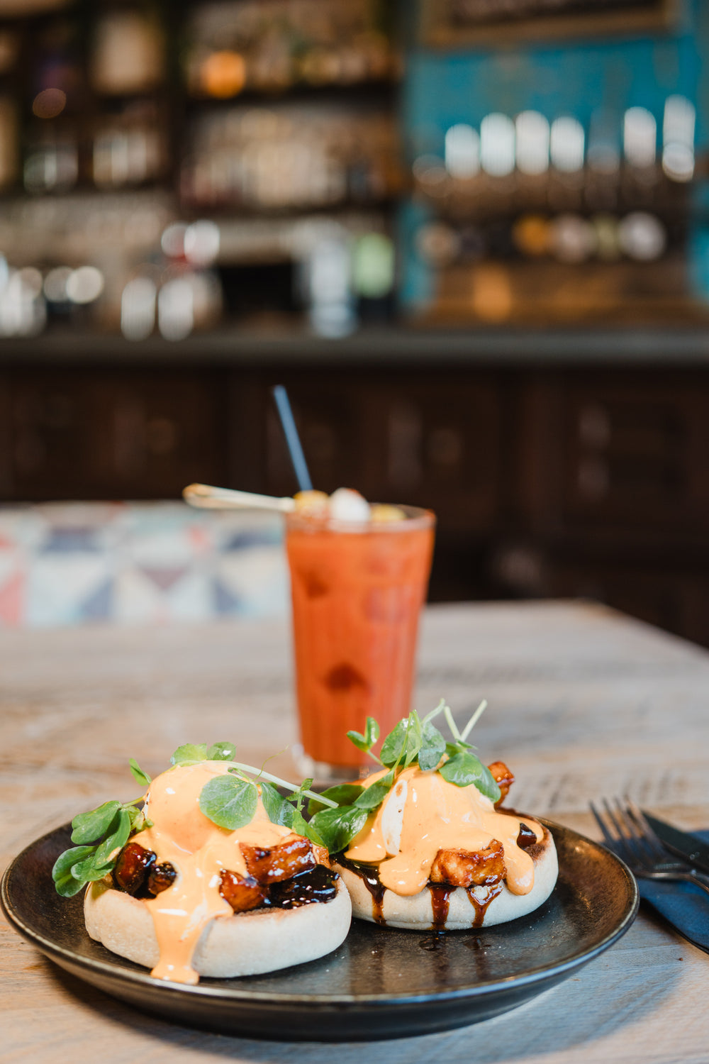 Chorizo and halloumi benedict topped with creamy sauce, fresh greens and served with an iced drink at Gas Street Social Birmingham.