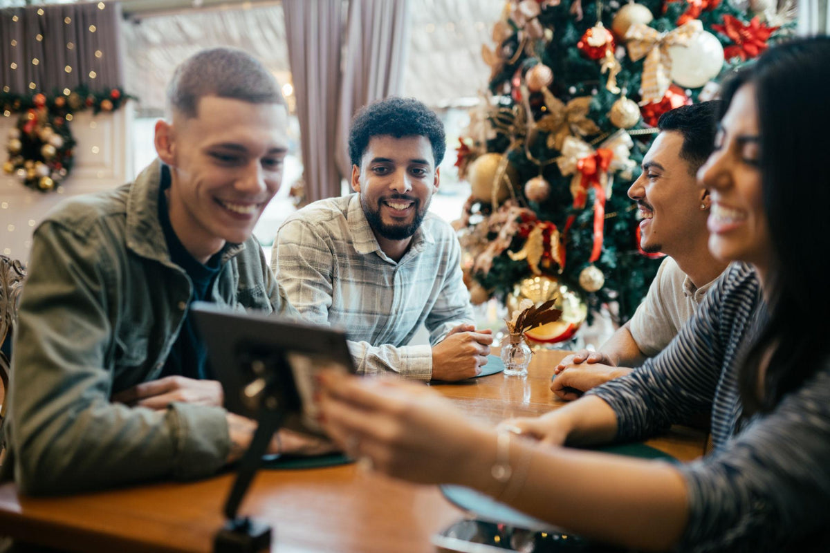 Group discussing plans for a Christmas celebration with a restaurant team member at a festive table.
