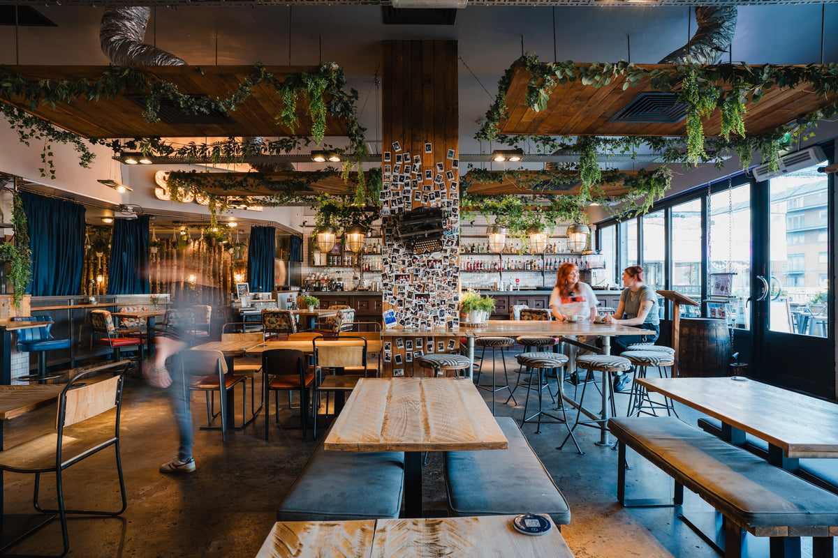 Interior of Gas Street Social restaurant and cocktail bar at The Mailbox in Birmingham city centre, featuring wooden tables, blue seating, hanging greenery and a stylish open-plan dining space.